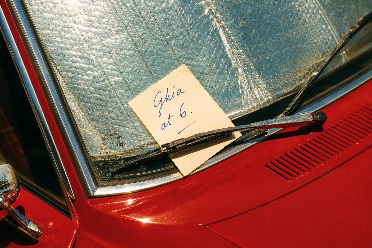 Ghia at six note tucked under a red car windshield wiper